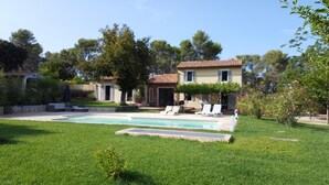 Propiedad residencial con piscina, zona de estar exterior y jardín.