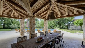 Eine Terrasse im Freien mit einem Holztisch, Stühlen und einer Steinsäule.