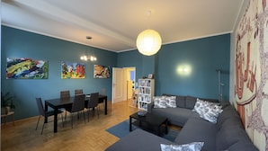A living room with a sofa, coffee table, and a dining area with chairs and a table. - Family-friendly 3-room apartment in the middle of hip Pieschen (Dresden)