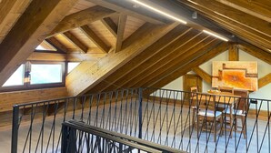 An attic room with exposed wooden beams, a metal railing, and a painting on the wall.