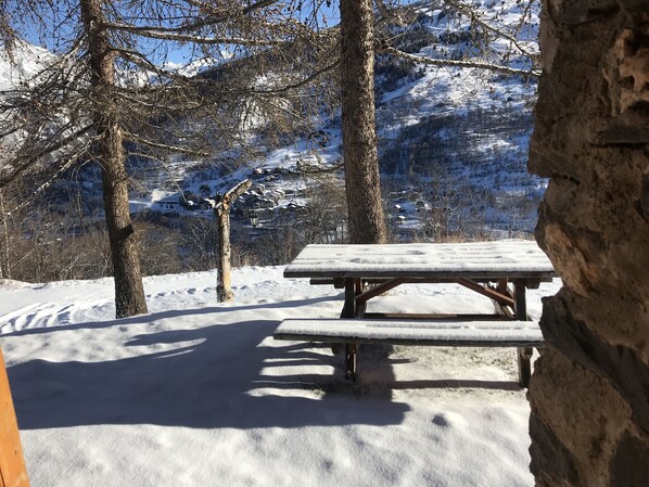 Sit and enjoy the serene mountain views from this outdoor picnic area surrounded by trees and a stone wall.