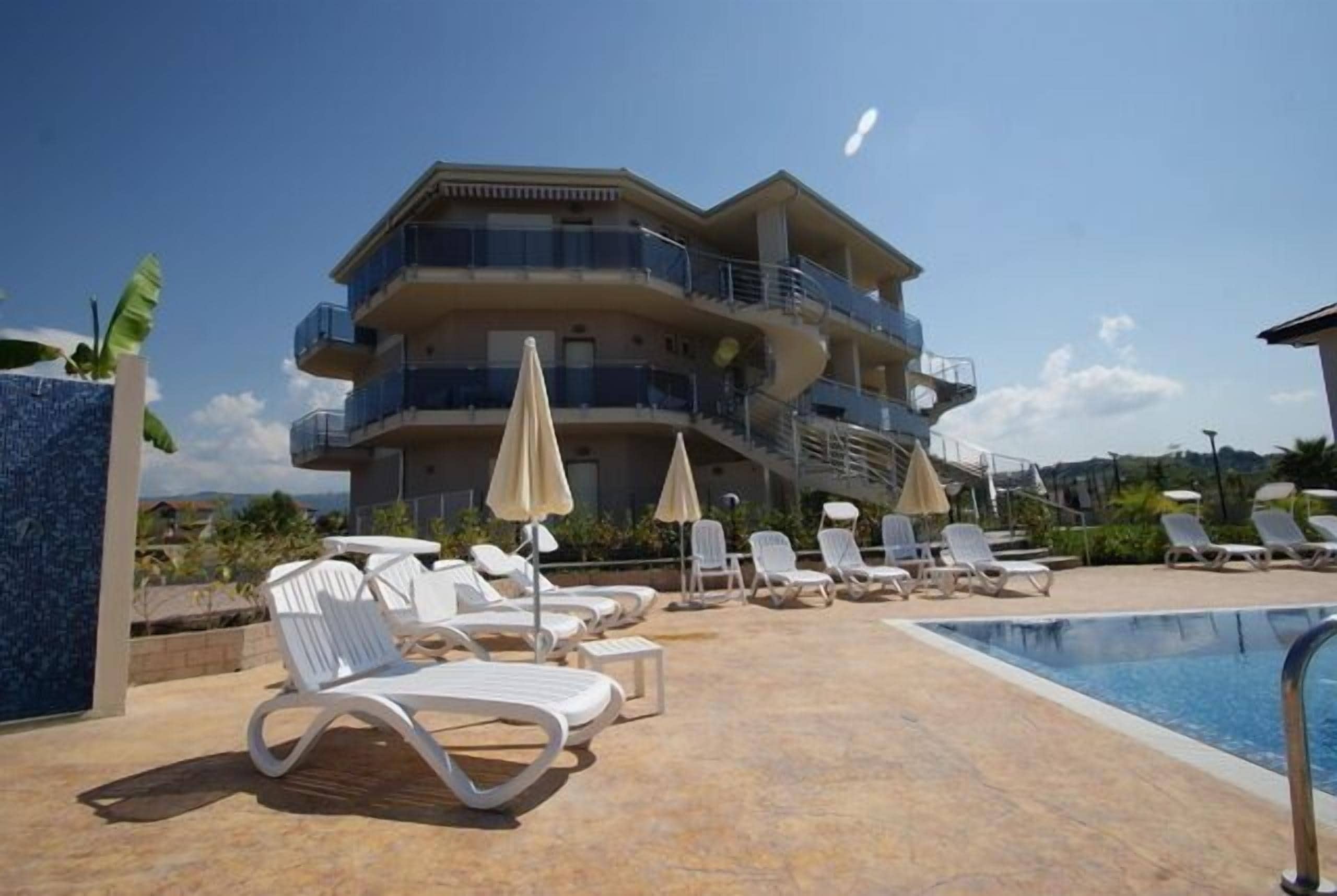 Een meerlaags hotel met een zwembadgedeelte, inclusief ligbedden en parasols.