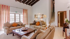 A spacious living area with two sofas, a coffee table, and a staircase leading to another floor.
