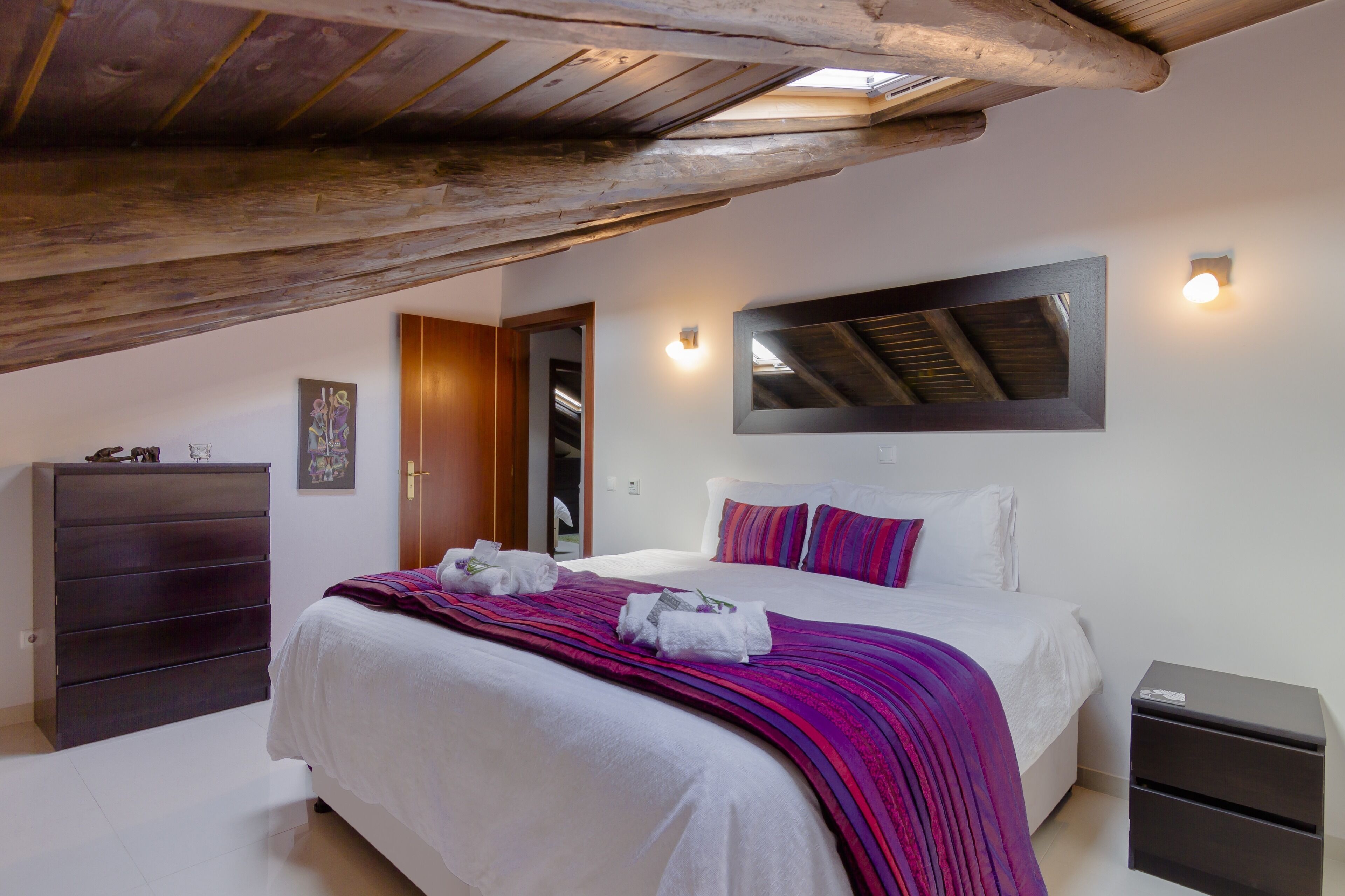 Un dormitorio con cama, cómoda, mesita de noche y espejo en la pared.