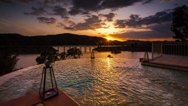 A sunset over a body of water with a bridge in the background.