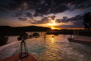 Um pôr do sol sobre a água, com uma ponte ao fundo.