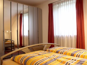 Relax in a cozy space with a comfortable bed, a wardrobe for storage, and a window with a view.