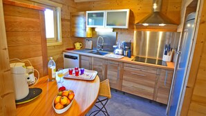 Una cocina compacta con armarios de madera, un refrigerador de acero inoxidable, un lavamanos y una ventana.