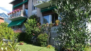 A two-story building with balconies, a stone wall, and a well-maintained garden. - Apartment - Bellagio House of the Sun (Bellagio)
