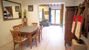A dining area with a wooden table and chairs, a large mirror, and a view of a staircase and a plant.