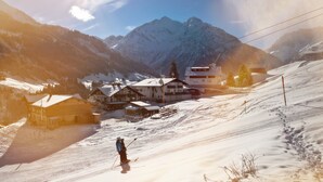 A ski resort with snow-covered slopes, buildings, and a mountain backdrop.