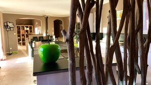 A modern kitchen with a green apple on the counter, wooden branches, and a dining area with chairs and a table. - GARD - Near UZES - Villa standing 8 people - Quiet - Swimming pool - Petanque - View (Rousson)