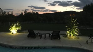A poolside area with lounge chairs and a table, surrounded by a fence and trees. - GARD - Near UZES - Villa standing 8 people - Quiet - Swimming pool - Petanque - View (Rousson)