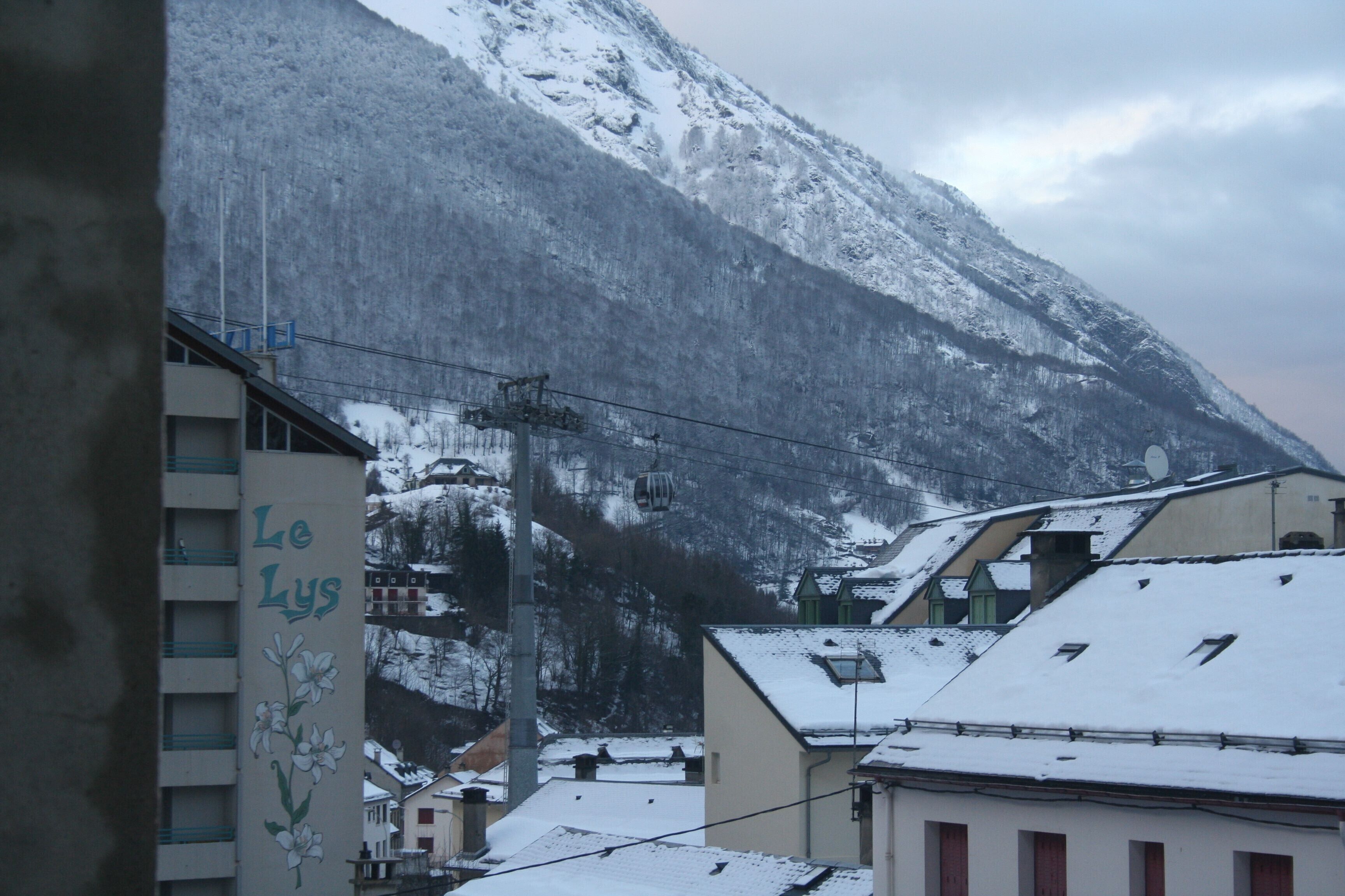 Un bâtiment sur lequel on peut lire l’inscription « Le Lys », avec une montagne enneigée en arrière-plan.
