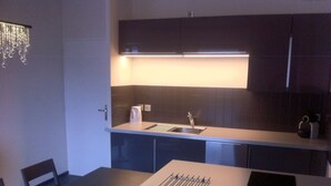 A compact kitchen with dark cabinetry, a stainless steel sink, and a modern light fixture above the countertop.