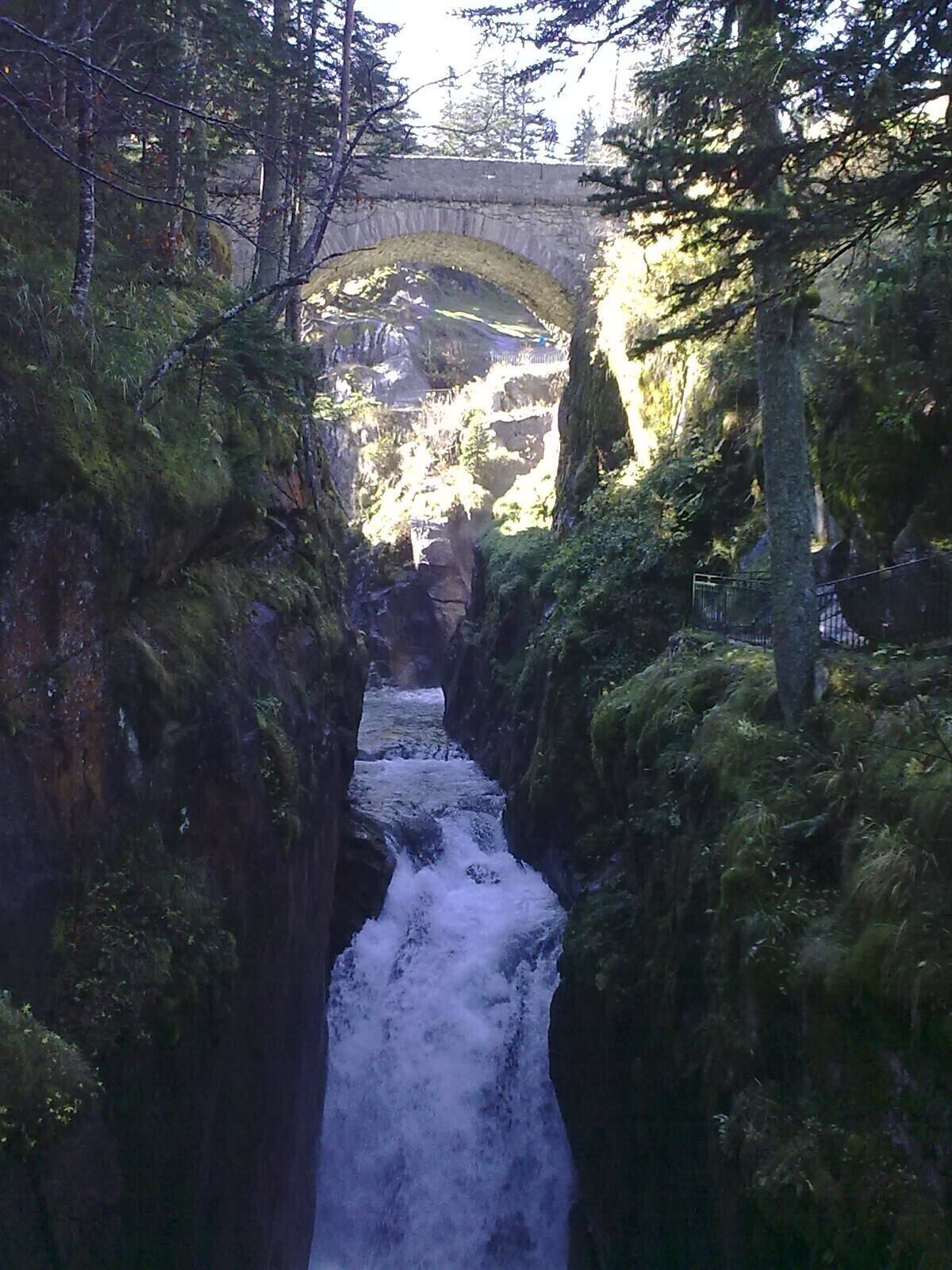 Un canal de agua estrecho y rocoso, con un puente al fondo.