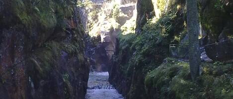 Un canal de agua estrecho y rocoso, con un puente al fondo.