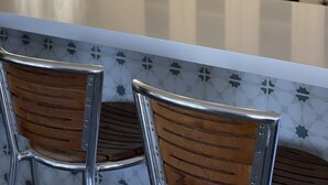 Une cuisine avec des meubles blancs, un îlot central doté de chaises et un vase rempli de fleurs.