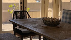 Un coin repas avec une table et des chaises, une vue sur la plage et un balcon doté d’une balustrade.