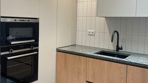 Una cocina moderna con armarios blancos, un horno negro, encimera de madera y grifo negro.