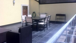 Un patio exterior con mesa y sillas, una manguera y una mesita.