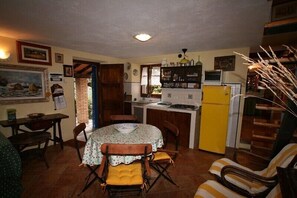 A compact kitchen with a dining table, chairs, a refrigerator, and a small island. - DELICIOUS RUSTIC WITH PRIVATE GARDEN AND TERRACE A FEW KM. FROM THE SEA.  (Retignano)