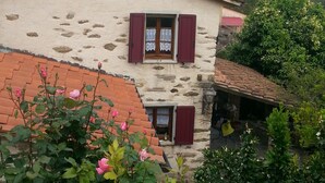 A rustic stone building with red shutters, a tiled roof, and a small porch area. - DELICIOUS RUSTIC WITH PRIVATE GARDEN AND TERRACE A FEW KM. FROM THE SEA.  (Retignano)