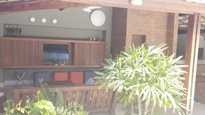 Una sala de estar con televisor, armarios de madera y un banco.