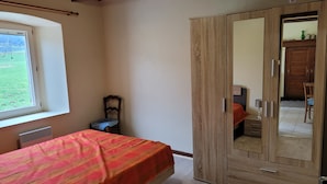 A bedroom with a bed, a wardrobe, a chair, and a window.