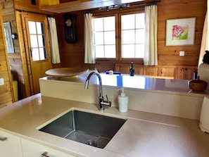 A kitchen with a stainless steel sink, wooden cabinets, a clock, and a window with curtains. - 4 * chalet: top equipment, fireplace, free Wi-Fi, near ALETSCHARENA (Breiten ob Mörel)