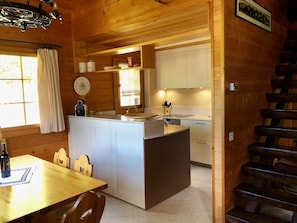 A wooden interior with a kitchen area featuring a central island, a dining table with chairs, and a staircase. - 4 * chalet: top equipment, fireplace, free Wi-Fi, near ALETSCHARENA (Breiten ob Mörel)