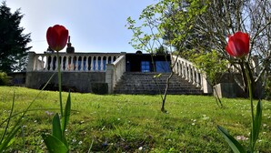 A building with a staircase leading to a door, surrounded by grass and flowers.