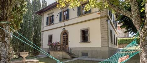 A two-story building with a garden, a hammock, and a fountain.