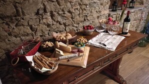 A wooden table with various food items, including cheese, bread, and fruits, set against a stone wall. - Apartment in Country Villa and  SPA (Vicchio (Firenze))