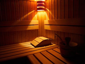 Un sauna avec des bancs en bois et un système de chauffage intégré aux bancs.