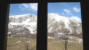 Due finestre con vista su un paesaggio montuoso, tra cui cime innevate e un piccolo villaggio con edifici.