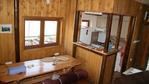 Un interno in legno con un tavolo da pranzo, panche, una finestra e un angolo cottura.