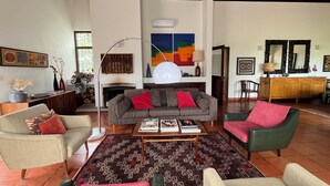Una sala de estar con chimenea, un sofá, una mesa de centro y un comedor con aparador y sillas.