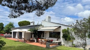 Una casa moderna con un patio, muebles de exterior y un amplio ventanal con vistas al jardín.