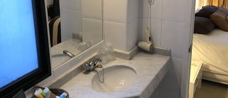 Un baño moderno con un espejo grande, un lavamanos y una zona de ducha.