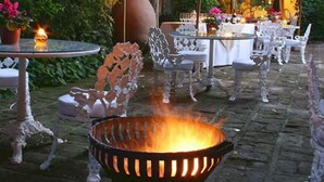 Ein Essbereich im Freien mit weißen Stühlen und einer zentralen Feuerstelle.