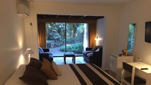 Ein Schlafzimmer mit Bett, Schreibtisch, Stuhl und Blick auf den Garten.