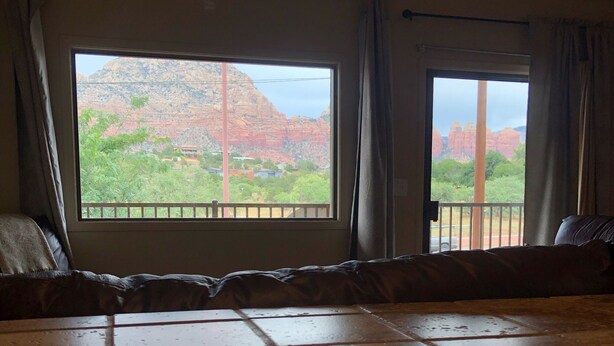 Ein Zimmer mit einem großen Bett, Blick auf rote Felsformationen und einem Balkon mit Geländer.