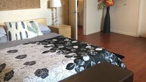Ein Schlafzimmer mit Bett, Nachttisch, Lampe und einer Blumenvase.