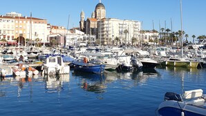 A marina with various boats docked, a prominent building with a dome in the background, and a clear blue sky. - Flat with balcony and sea view, very central.  (Saint-Raphaël)