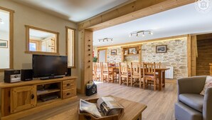 Un salon chaleureux avec un téléviseur, des meubles en bois et un mur en pierre.