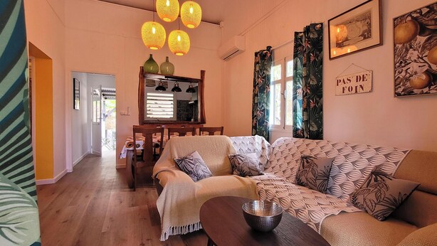 A cozy living room with a sofa, a coffee table, and a wooden chair. There are decorative lanterns hanging from the ceiling and a mirror on the wall. - La Marmandia - Rural house in the heights of western Reunion (La Saline Les Hauts)