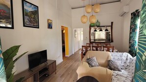 A living room with a TV, sofa, and dining area. - La Marmandia - Rural house in the heights of western Reunion (La Saline Les Hauts)
