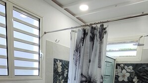 A bathroom with a shower, tiled walls, a window with blinds, and a wooden stool. - La Marmandia - Rural house in the heights of western Reunion (La Saline Les Hauts)