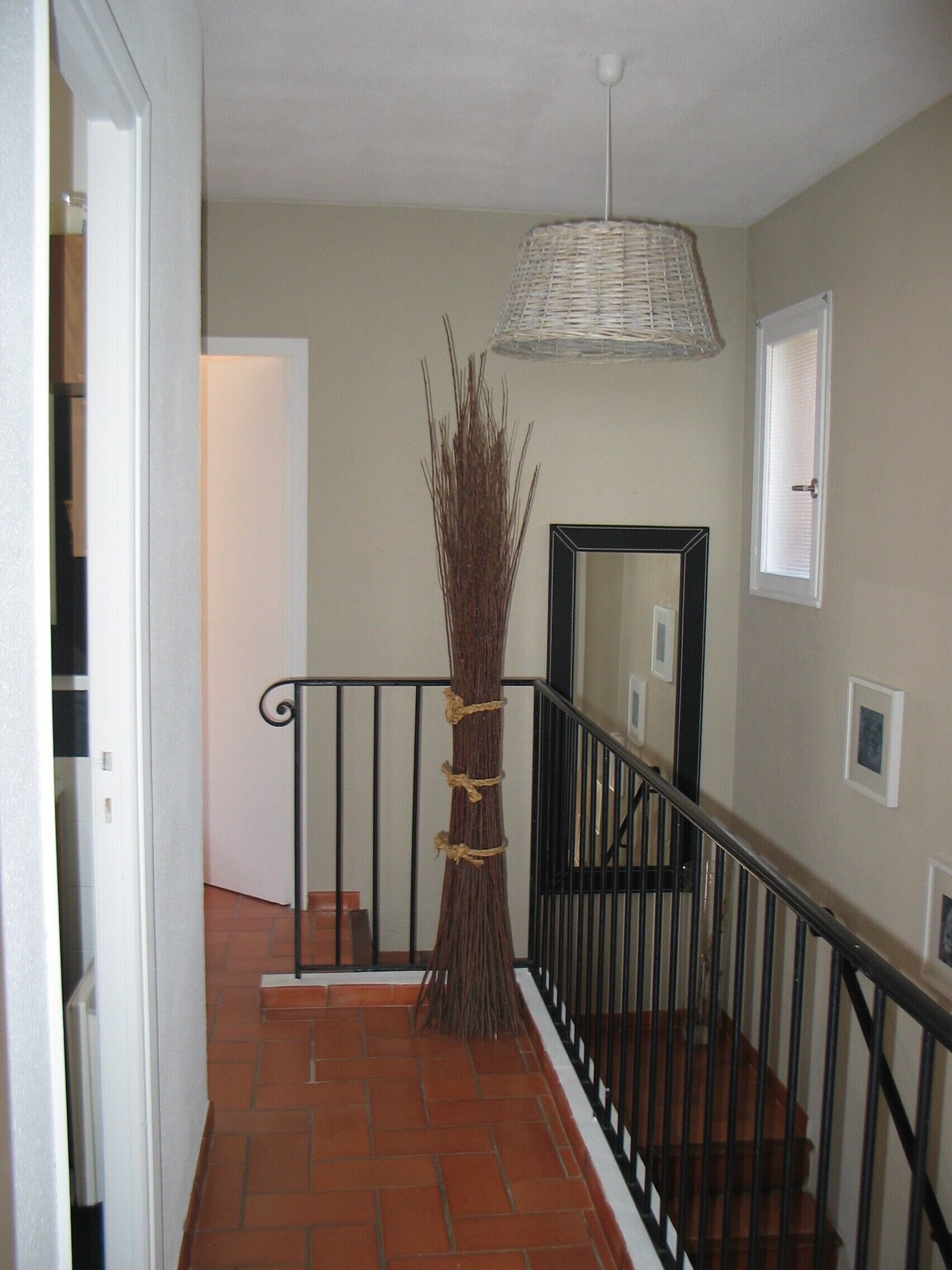 Un escalier avec une rampe, un luminaire suspendu et une grande plante décorative.